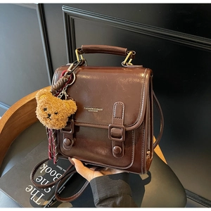 Detail der dunkelbraunen Vintage-Handtasche aus Kunstleder mit Schnallen und Plüschbär-Anhänger