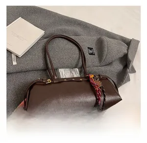 Vue détaillée du sac baguette vintage marron foncé avec texture cuir sur manteau