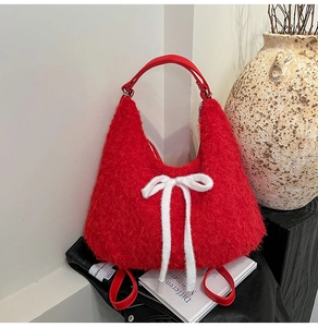 Detail of red plush hobo bag featuring a soft faux fur texture and white knit bow