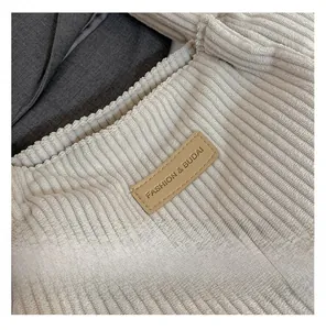 Detailed close-up of corduroy texture and embossed leather logo on the white tote bag
