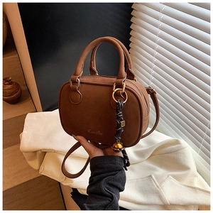 Detail of vintage brown leather crossbody bag with distinctive bell and cord charm