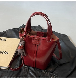 Detail of wine red leather bucket bag with fashion embossing and brown bear charm