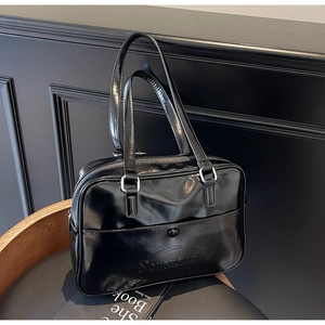 Detail of black glossy patent leather shoulder bag with embossed logo and silver hardware