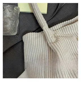 Detail shot of white corduroy tote bag showing thick ribbed fabric and shoulder strap