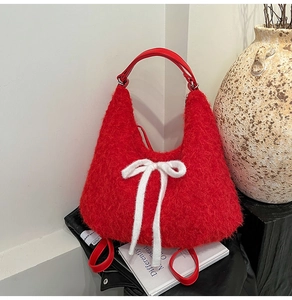Detailed view of red plush Hobo bag with white ribbon bow and leather handle