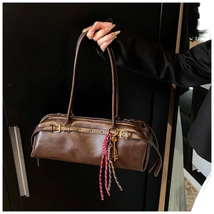 Détail du sac baguette en cuir marron avec breloque clé en bronze et glands tissés
