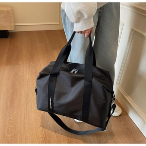 Gros plan d'un sac de voyage en nylon noir avec poignées renforcées et bandoulière amovible