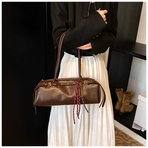 Détail du sac baguette marron foncé avec boucles de ceinture et cordon tressé