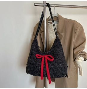 Detail of black tweed hobo bag with a plush red bow and metallic silver threads