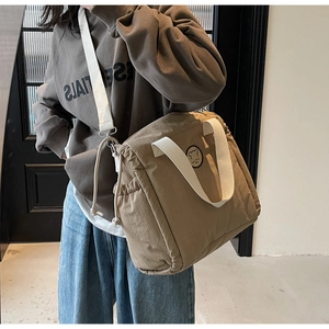 Detail of coffee canvas tote bag showing drawstring closure and crossbody strap in use