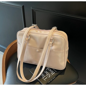 Detail of light pink faux leather shoulder bag with embossed logo on front pocket