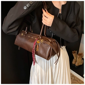 Détail d'un sac cylindre marron avec breloque clé dorée et pompon coloré