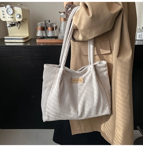 Detailed texture of white corduroy tote bag featuring leather brand patch and long handles