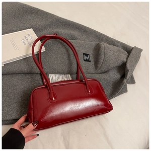 Close-up of glossy dark red oil wax leather handbag with fine texture and matching strap