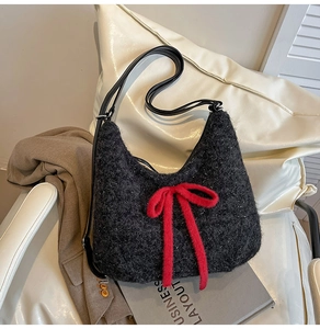 Close-up of black plush shoulder bag featuring a large red bow and subtle glitter detail