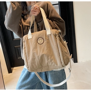 Dettaglio della borsa tote in tela kaki con ricamo a orso e tracolla regolabile