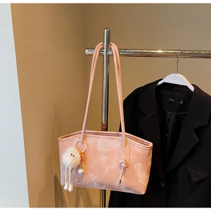 Detailed shot of pink tote bag with cloud print and a plush ball charm on a metal hanger
