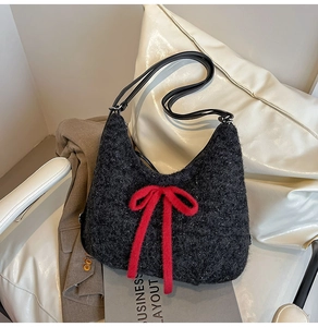 Detail of dark gray plush hobo bag with a vibrant red bow accent and black straps
