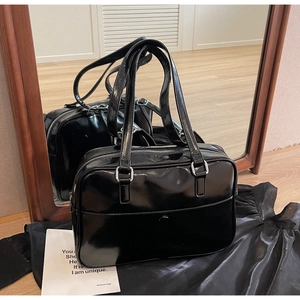 Close-up of black glossy shoulder bag showing mirror texture and silver hardware details
