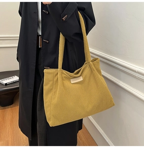 Detail of mustard yellow corduroy tote bag showing ribbed texture and fashion label