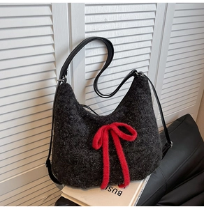 Close-up of black plush hobo bag with red fuzzy bow and sparkling silver glitter detail