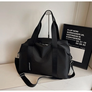 Détail du cabas en nylon noir avec bandoulière réglable et poignée en sangle avec logo