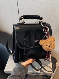 Schwarze Retro-Handtasche aus Lackleder mit Doppelriemen und braunem Teddybär-Anhänger