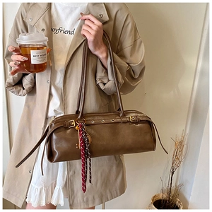 Détail du sac baguette marron foncé avec boucles dorées et foulard décoratif en soie