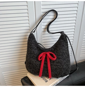 Detail of plush black tweed shoulder bag featuring a large vibrant red fuzzy bow accent