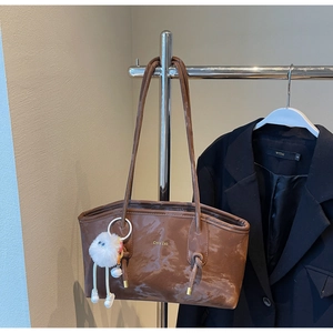 Detail of dark brown faux leather tote bag with marble texture and plush pendant charm