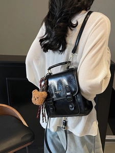 Vintage Lederrucksack in Schwarz mit Schnallen und Bärenanhänger getragen von Modell