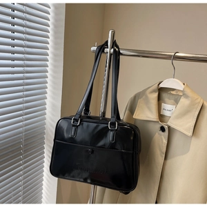 Detail of embossed logo on glossy black faux leather tote bag with dual shoulder straps