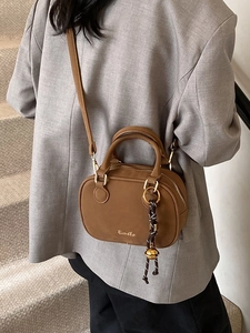 Brown rectangular crossbody bag with gold hardware and woven tassel on grey blazer outfit