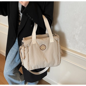 Detail of canvas tote bag with drawstring side pocket and round fashion bear patch