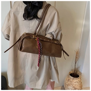 Détail du sac baguette marron foncé avec foulard en soie et breloque clé dorée
