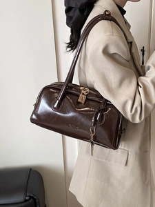 Glossy dark brown Boston bag with gold padlock and top handles shown on model