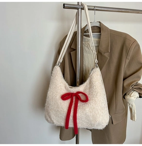 Detail of plush cream shoulder bag featuring a large red bow in a winter outfit setting