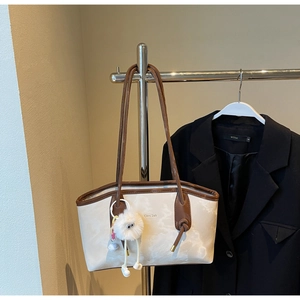 Detail of marble pattern tote bag with brown leather straps and plush eye pendant