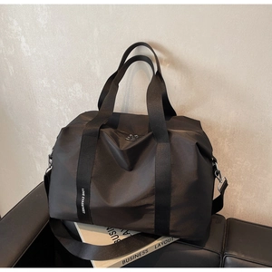 Détail du sac cabas en nylon noir montrant les boucles métalliques et la bandoulière large