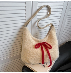Detail view of cream plush hobo bag with a red knit bow on a stylish magazine