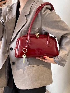 Deep red patent leather bowling bag with gold hardware and logo for daily commute
