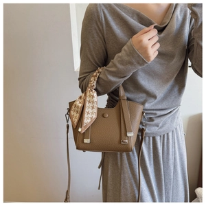 Detailed texture of brown litchi grain leather bucket bag with a stylish silk scarf