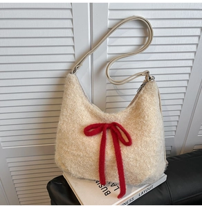 Detail of plush off-white shoulder bag featuring a prominent red knitted bow decoration