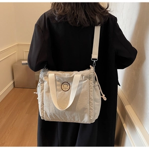 Dettaglio borsa a tracolla beige in nylon con patch orso e ampia tracolla regolabile
