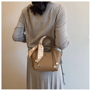 Detail of tan crossbody bag with lychee texture and houndstooth silk scarf on handle