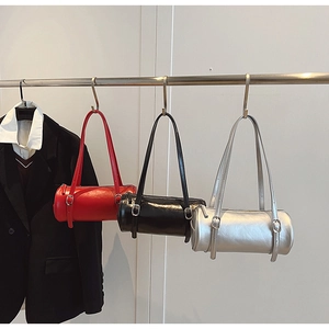 Detailed view of glossy cylinder shoulder bags in red, black, and silver with metal buckles