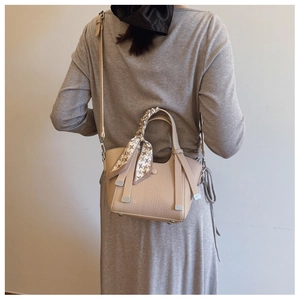 Detail of beige bucket bag with lychee texture and geometric pattern silk scarf wrap