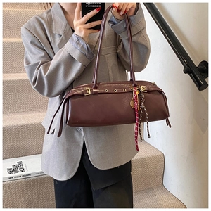 Détail d'un sac baguette vintage bordeaux avec sangle à boucle métal et pendentif tressé