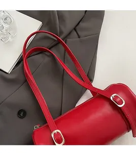 Detail of red cylindrical handbag with adjustable straps on a gray blazer