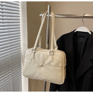Detail of a creamy white faux leather tote bag with embossed letters and silver hardware